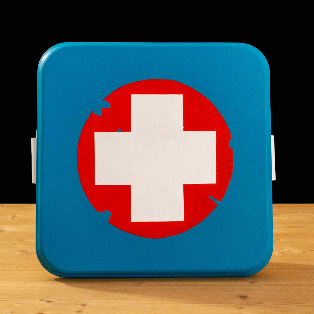 A TF2 Medium Health Kit Replica Props for cosplay featuring its blue lid with a white cross on a chipped paint red circle, the white body and its grey handles.
