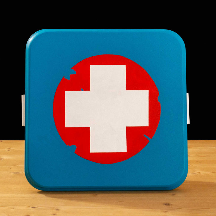 A TF2 Medium Health Kit Replica Props for cosplay featuring its blue lid with a white cross on a chipped paint red circle, the white body and its grey handles.