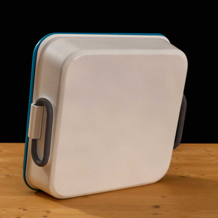 A TF2 Medium Health Kit Replica Props for cosplay featuring its blue lid with a white cross on a chipped paint red circle, the white body and its grey handles.