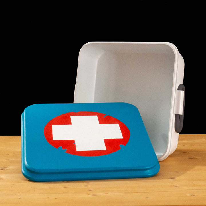 A TF2 Medium Health Kit Replica Props for cosplay featuring its blue lid with a white cross on a chipped paint red circle, the white body and its grey handles.